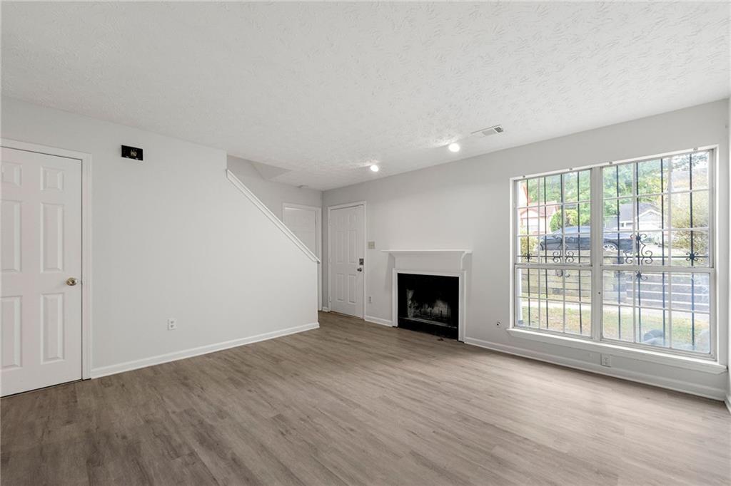 2575 Picardy Circle North, Unit B Atlanta, GA 30349 - Photo 4 of 20 an empty room with wooden floor fireplace and windows