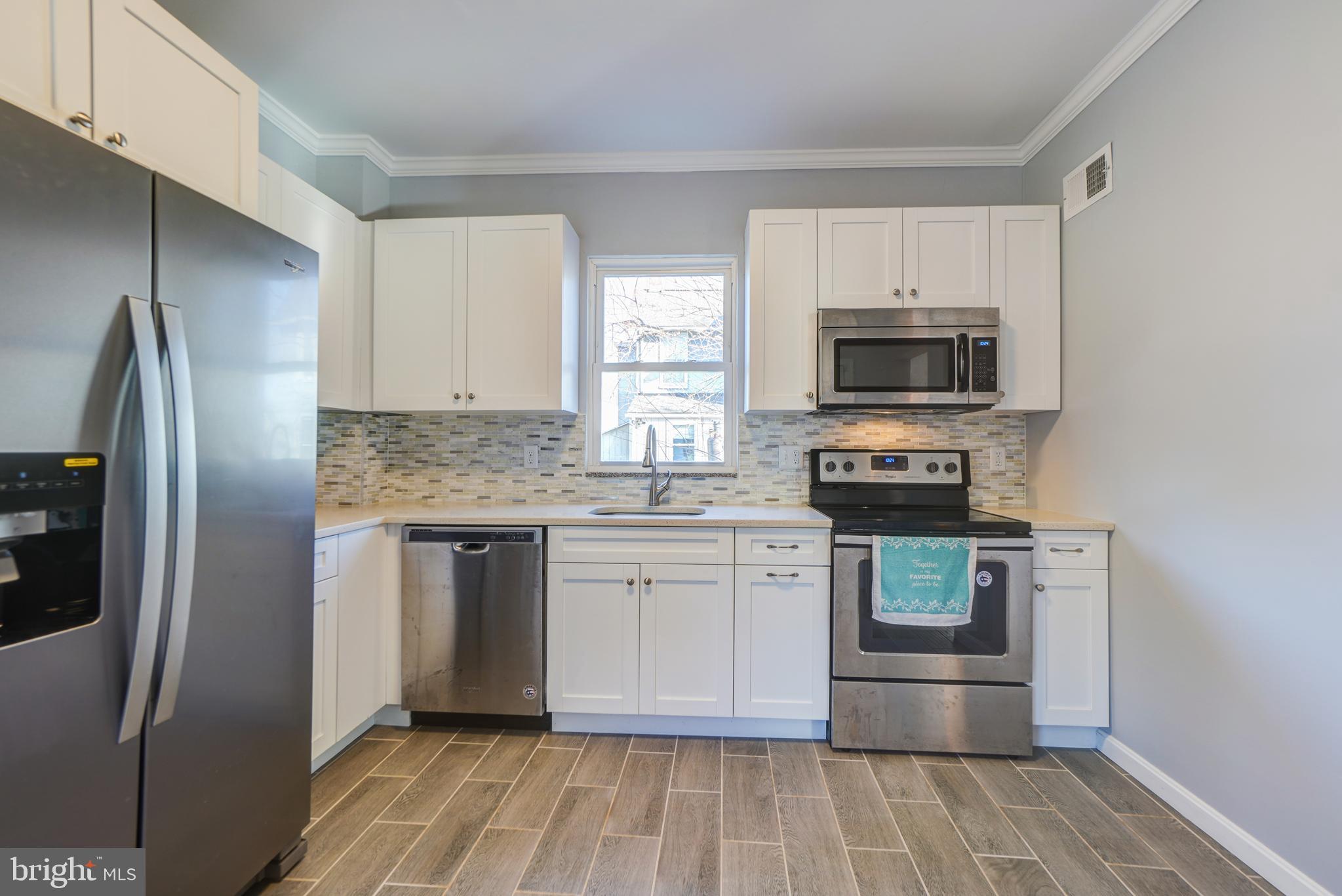 35 4th Street Laurel, MD 20707 - Photo 13 of 31 a kitchen with kitchen island granite countertop a stove microwave and refrigerator