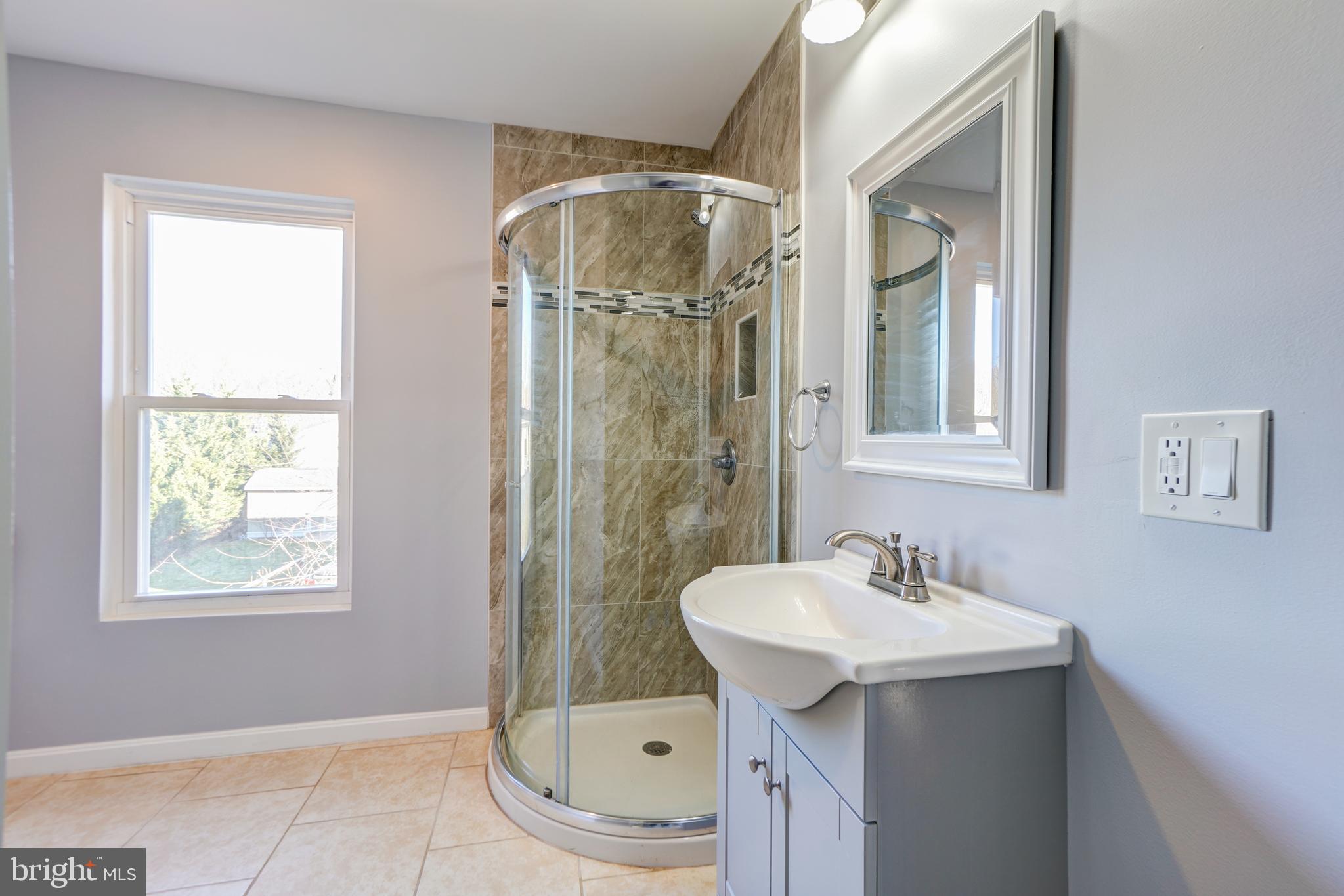 35 4th Street Laurel, MD 20707 - Photo 25 of 31 a bathroom with a sink a mirror and a shower