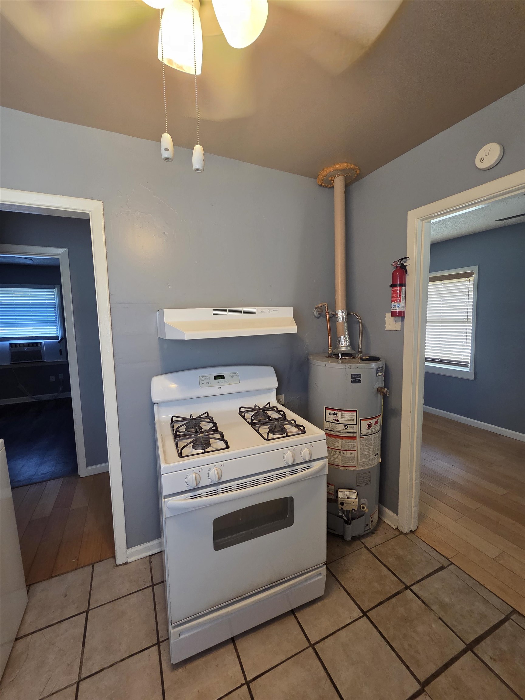 3166 Winslow Road Memphis, TN 38109 - Photo 13 of 17 Kitchen featuring white gas range oven, water heater, light tile patterned floors, and under cabinet range hood
