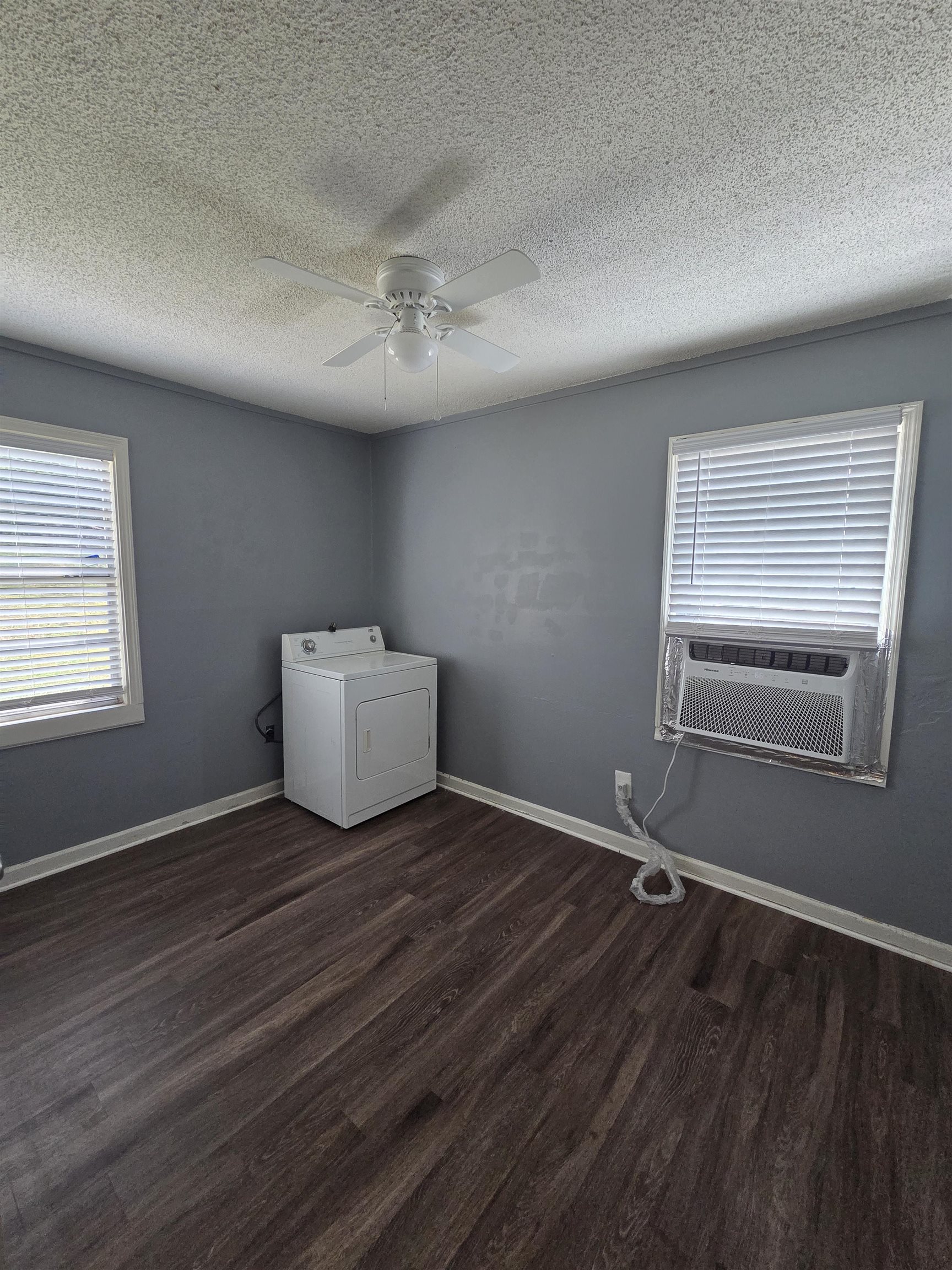 3166 Winslow Road Memphis, TN 38109 - Photo 8 of 17 Spare room with healthy amount of natural light, washer / dryer, dark wood-style floors, a textured ceiling, and cooling unit