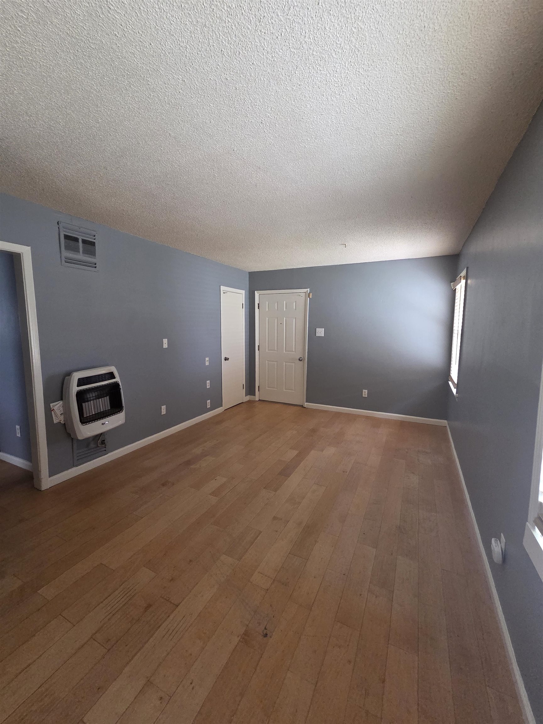 3166 Winslow Road Memphis, TN 38109 - Photo 9 of 17 Unfurnished living room with wood-type flooring, a textured ceiling, and heating unit