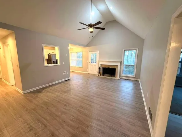 an empty room with wooden floor fireplace and windows