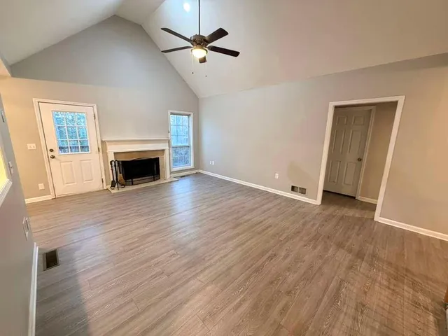 an empty room with wooden floor fireplace and ceiling fan