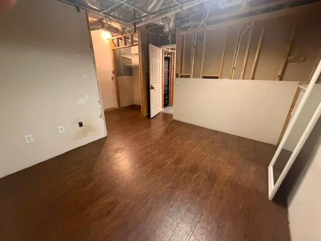 a view of empty room with wooden floor and fan