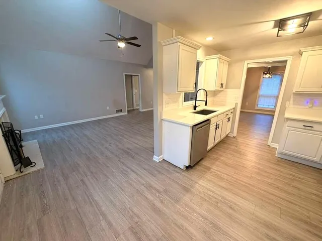 a large kitchen with stainless steel appliances a large counter top and a wooden floors