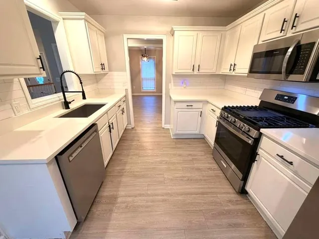 a kitchen with granite countertop wooden cabinets a stove top oven and stainless steel appliances