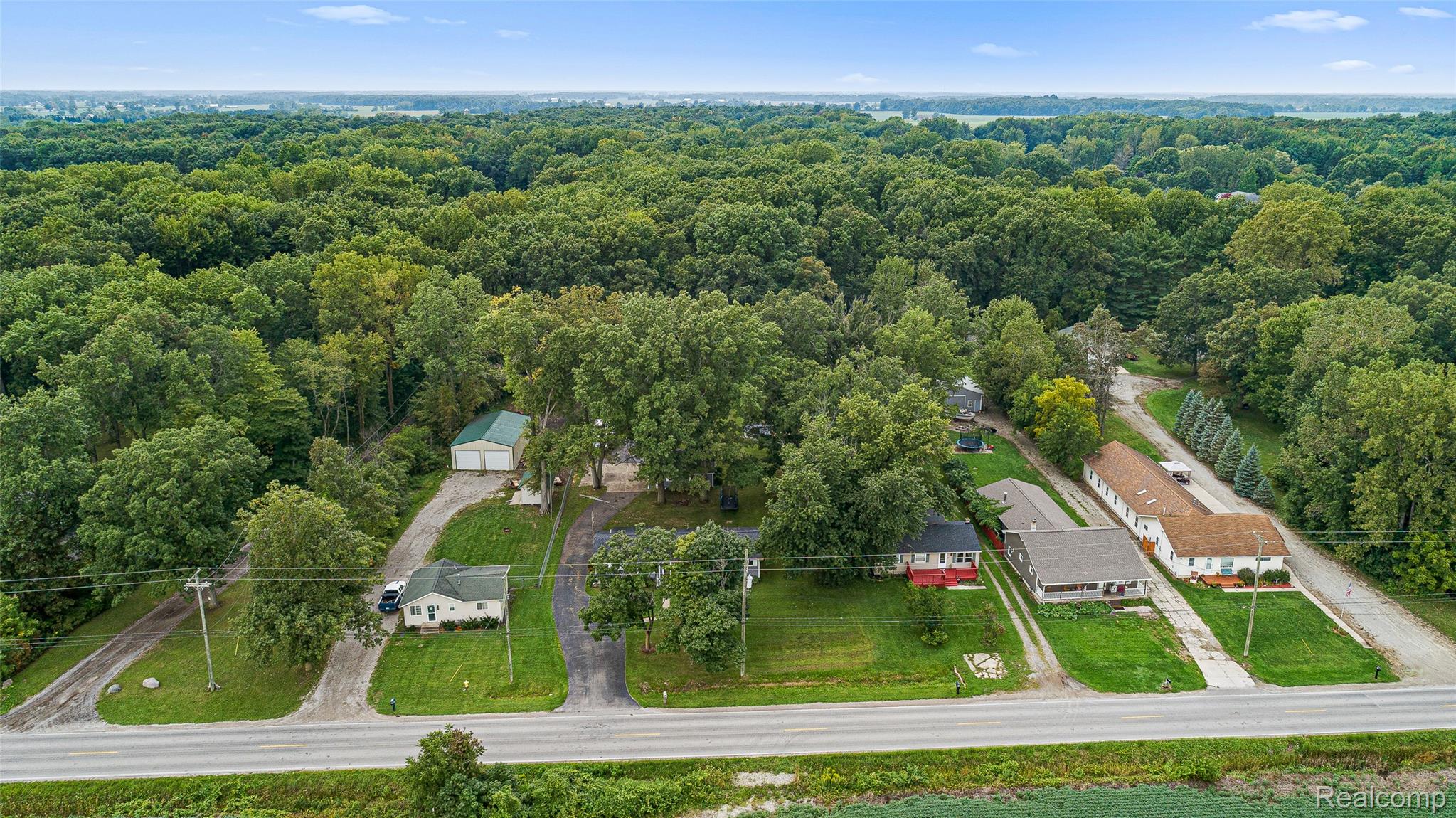 9561 Exeter Road Carleton, MI 48117 - Photo 2 of 46 Expansive wooded surroundings, multiple residential structures, paved driveways, a large detached garage, and a direct road frontage