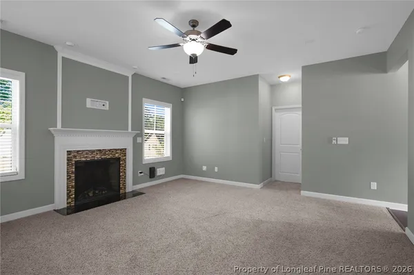 a view of a livingroom with a fireplace a chandelier and windows