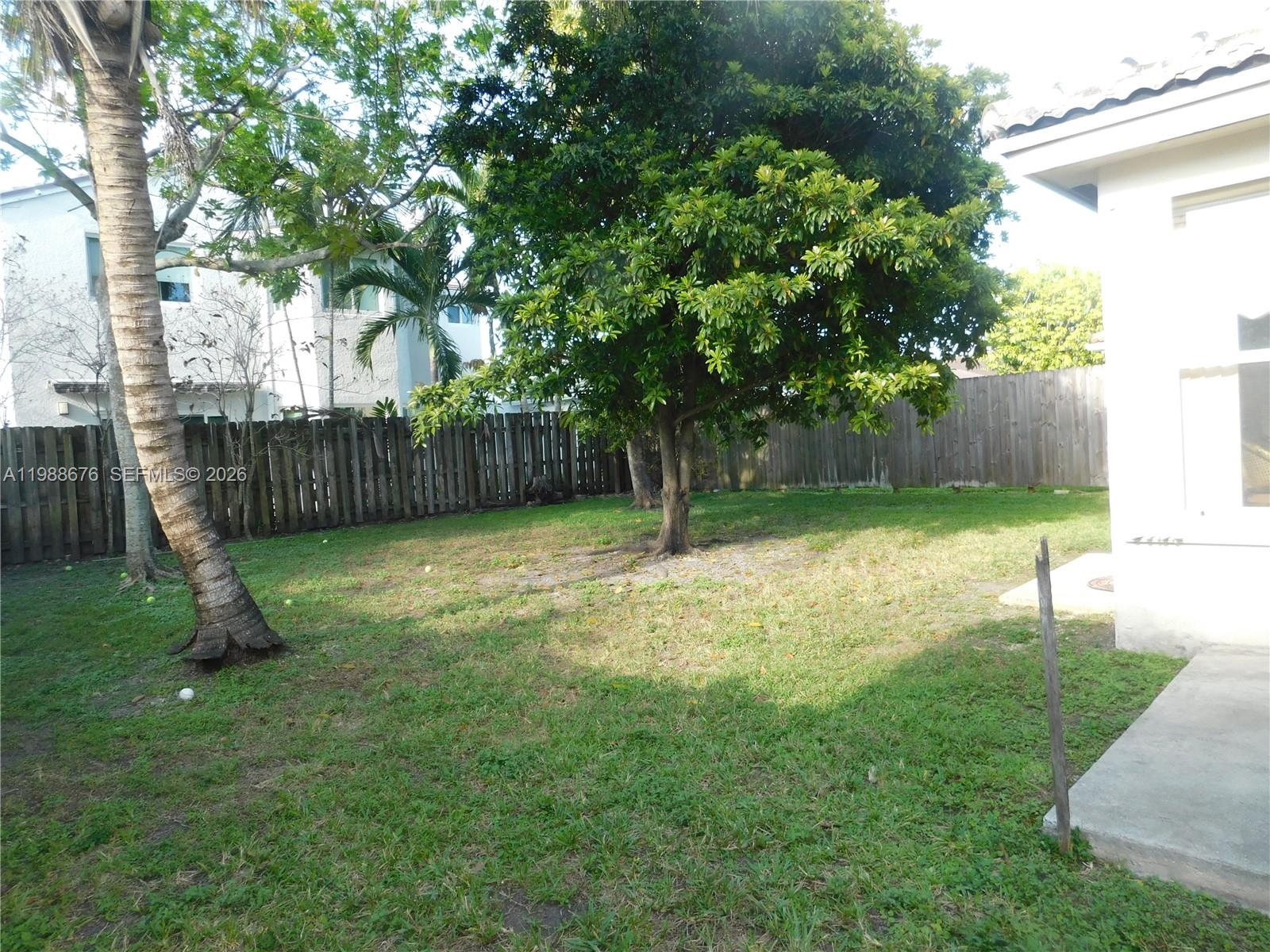 15871 Southwest 82nd Street Miami, FL 33193 - Photo 7 of 7 a view of a backyard with a tree and wooden fence