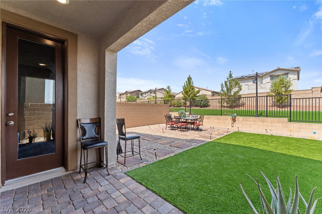 8879 Roadrunner Ravine Street Las Vegas, NV 89166 - Photo 38 of 39 A spacious backyard retreat features a covered patio, paved outdoor dining area, and a lush artificial turf lawn.