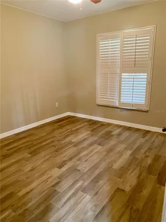 a view of an empty room with wooden floor and a window