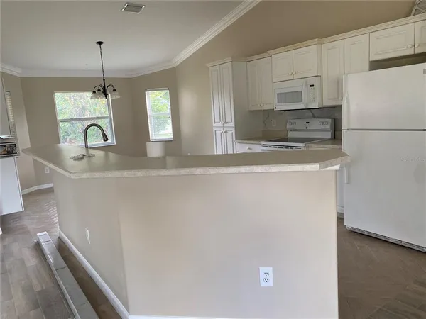 a kitchen with stainless steel appliances granite countertop a sink a refrigerator a stove and white cabinets with wooden floor