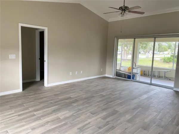 an empty room with wooden floor fan and windows