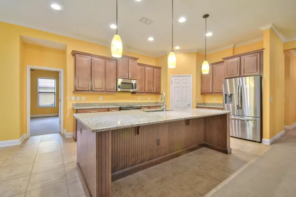 a kitchen with kitchen island granite countertop a sink appliances and cabinets