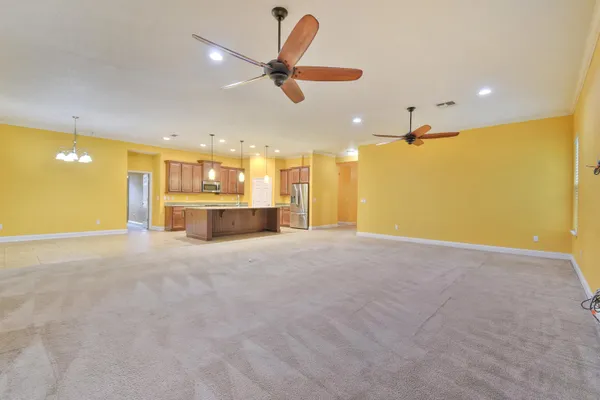a large kitchen with a large counter top a sink stainless steel appliances and cabinets