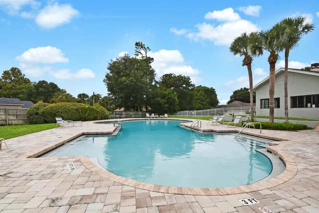 a view of a swimming pool with a yard and palm trees
