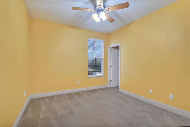 a view of a big room with windows and chandelier fan