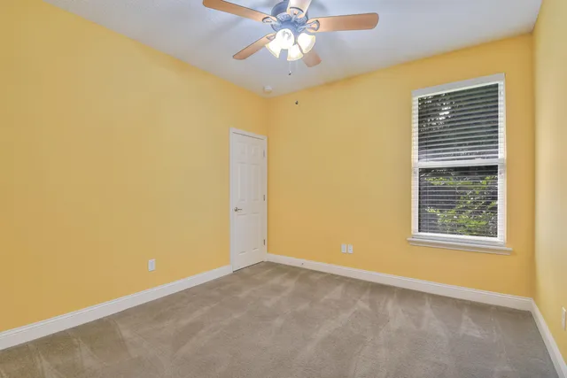 an empty room with windows and chandelier fan
