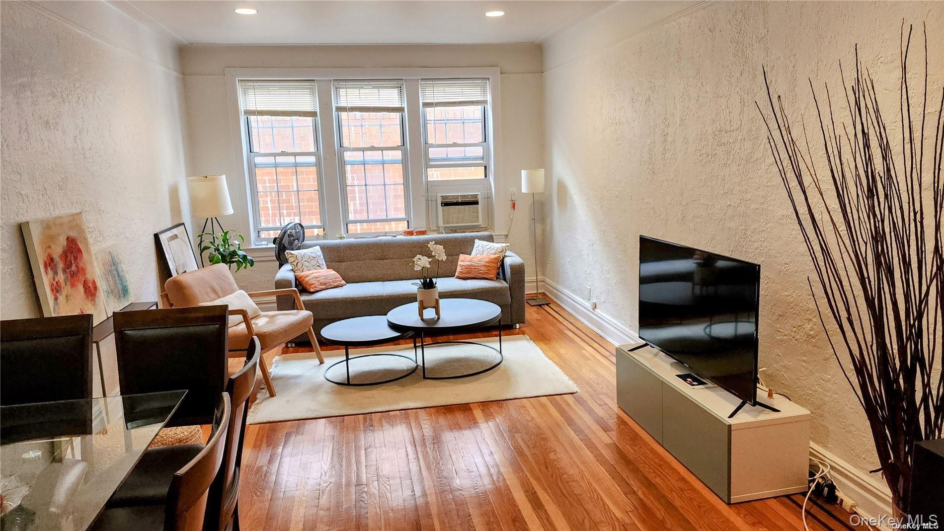4 Maple Drive, Unit 6H Great Neck, NY 11021 - Photo 2 of 14 a living room with furniture and a flat screen tv