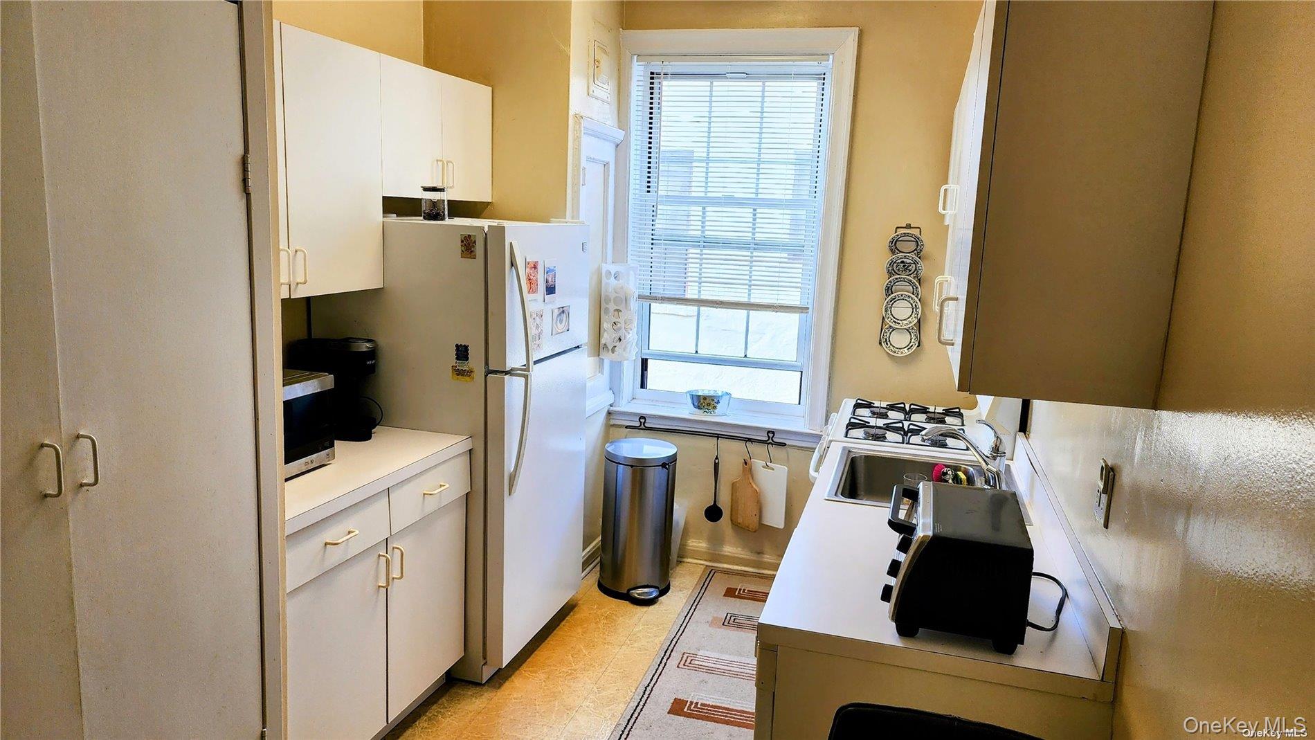 4 Maple Drive, Unit 6H Great Neck, NY 11021 - Photo 8 of 14 a kitchen with a refrigerator and window