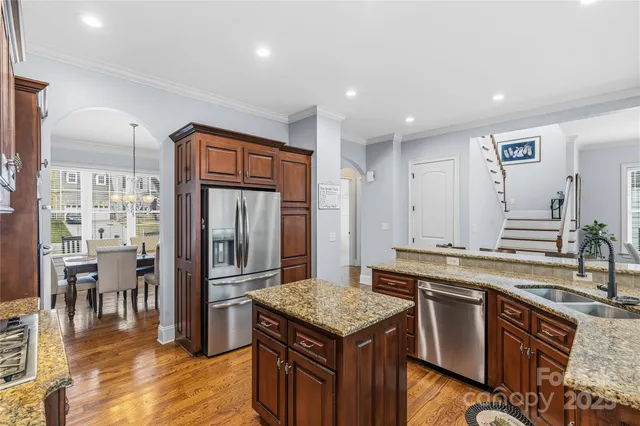 a view of a kitchen counter top space with stainless steel appliances granite countertop a stove and a view of living room