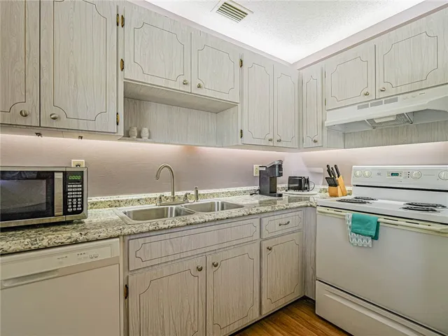 a kitchen with stainless steel appliances granite countertop a sink dishwasher stove and white cabinets