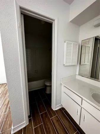 a bathroom with a granite countertop toilet sink and mirror
