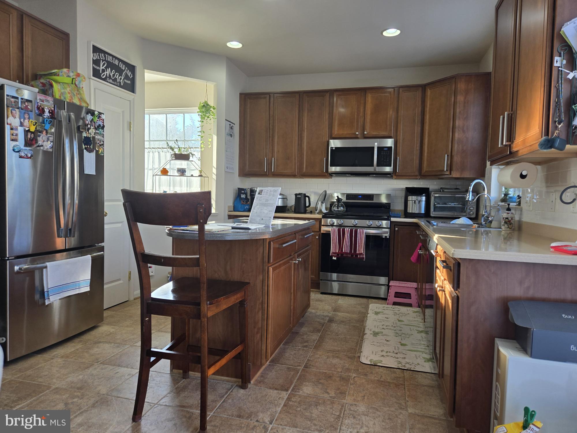 9254 Cascade Falls Drive Bristow, VA 20136 - Photo 5 of 14 a kitchen with stainless steel appliances granite countertop a stove top oven a sink dishwasher a dining table and chairs