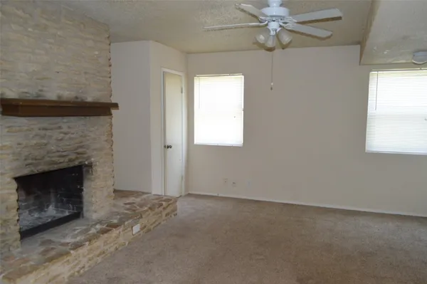 an empty room with windows and fireplace