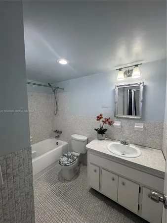 a bathroom with a double vanity sink a toilet and bathtub
