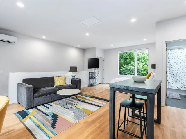 a living room with furniture a flat screen tv and a floor to ceiling window