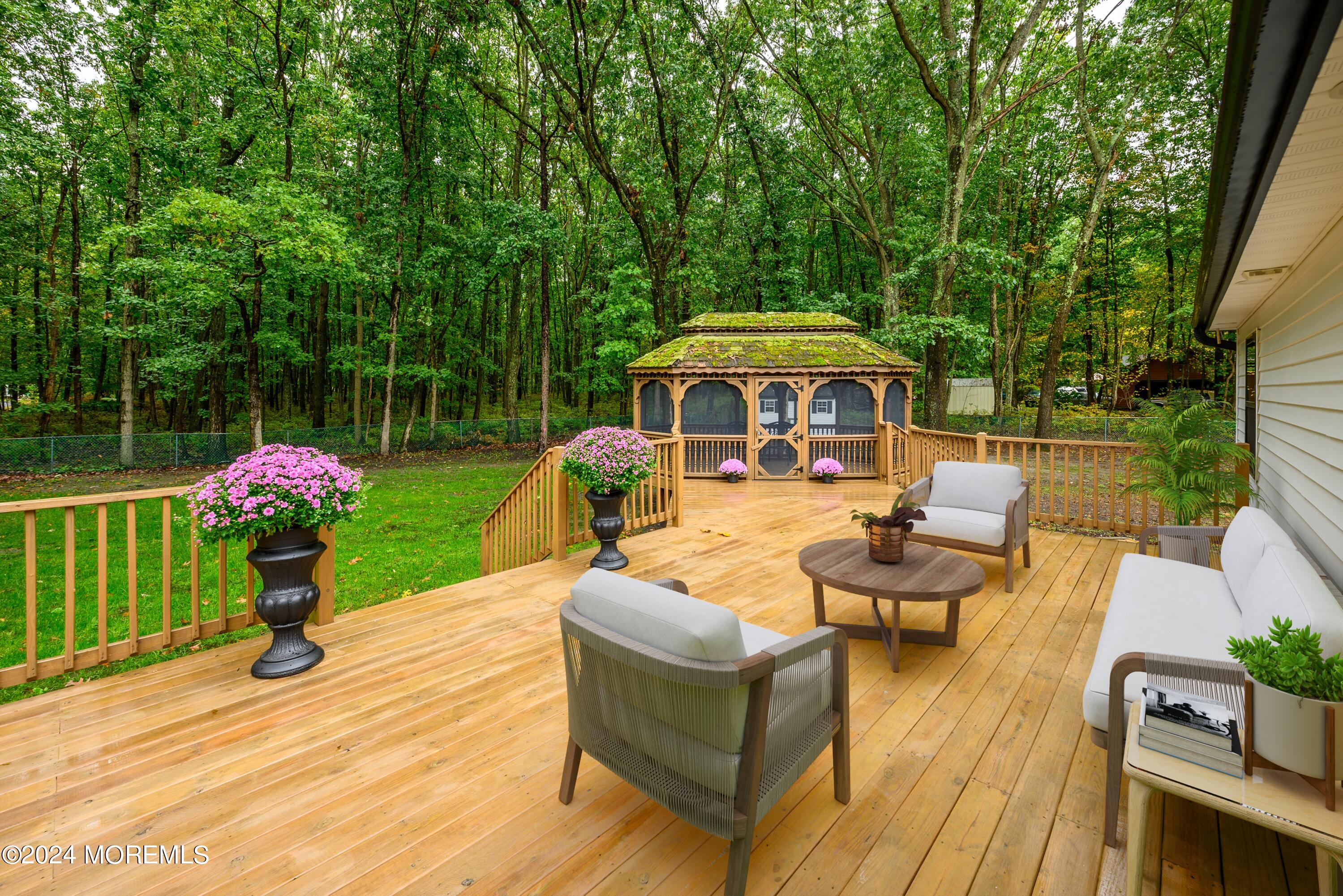 50 Old Turkey Swamp Road Freehold, NJ 07728 - Photo 18 of 23 a view of a patio with couches table and chairs under an umbrella with large trees