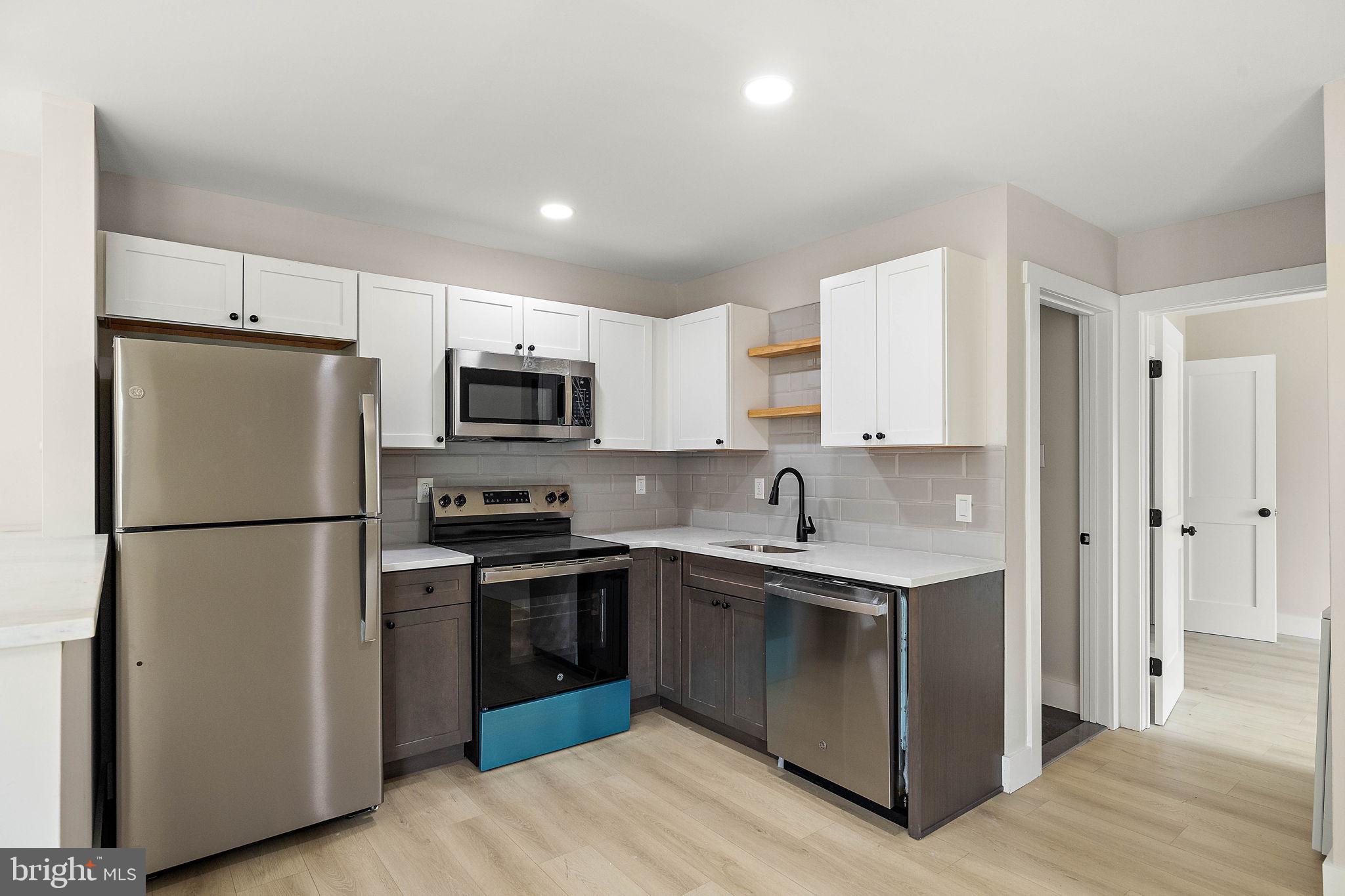 a kitchen with a sink a refrigerator and white cabinets