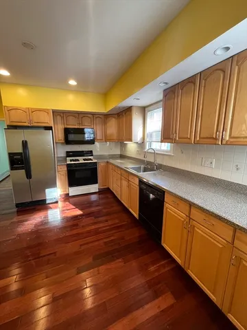 a kitchen with stainless steel appliances wooden floors and wooden cabinets