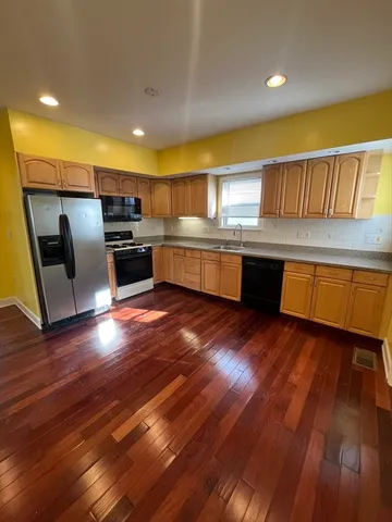 a kitchen with stainless steel appliances wooden floors and wooden cabinets