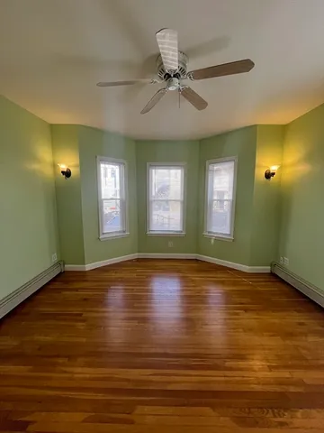 a view of empty room with wooden floor and fan