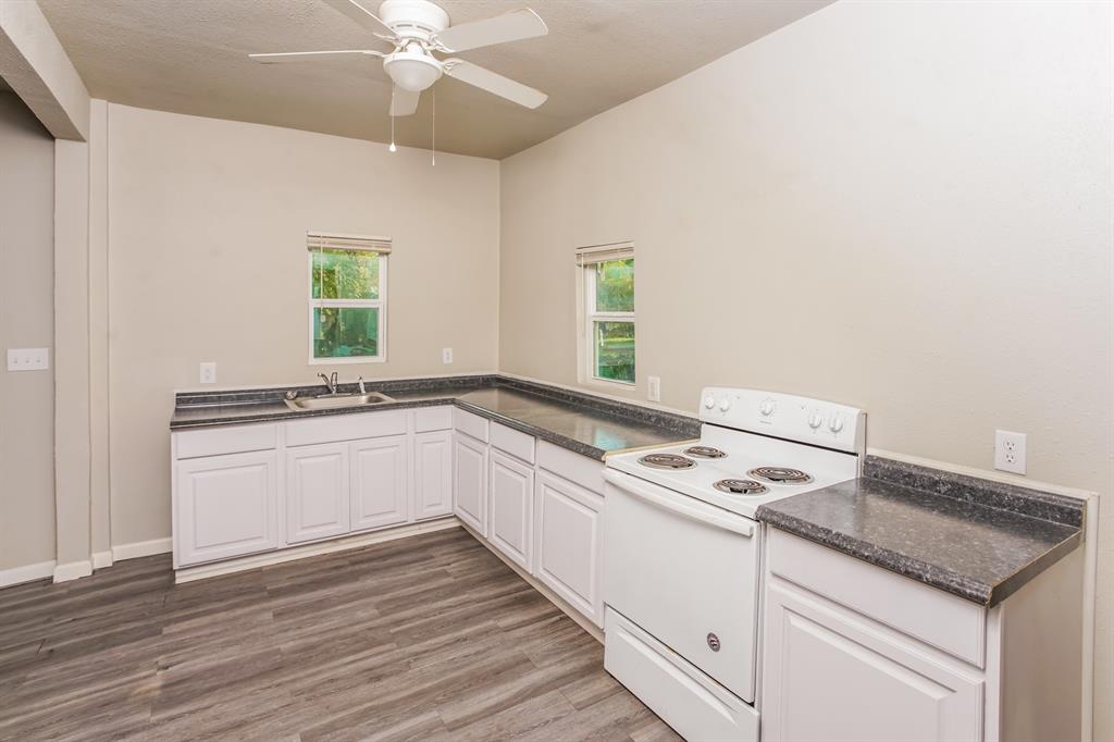 2402 Summer Avenue Waco, TX 76708 - Photo 5 of 15 Kitchen area featuring wood-finish flooring, white cabinetry, dark countertops, a double basin sink, and a white electric range