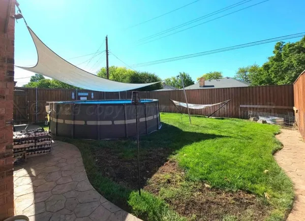 a view of a backyard with a swing chair and wooden fence