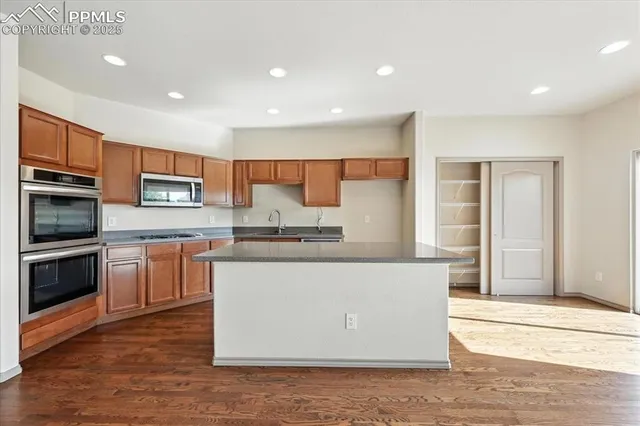a kitchen with stainless steel appliances granite countertop a stove top oven a sink and a refrigerator