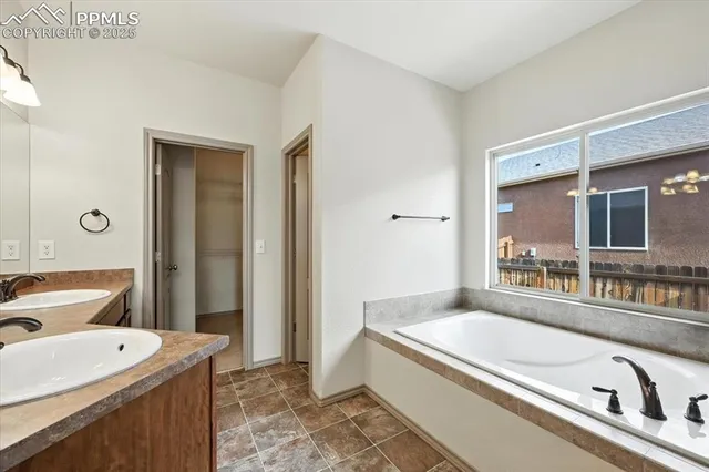 a bathroom with a granite countertop tub sink and mirror