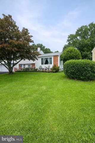 a view of a house with a big yard and large trees