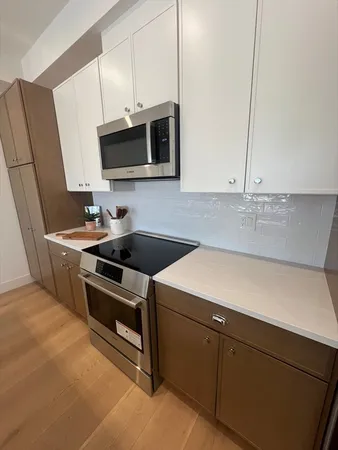a kitchen with stainless steel appliances a sink dishwasher stove and microwave with wooden floor