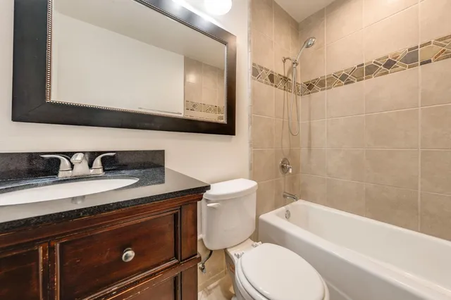a bathroom with a granite countertop toilet sink a mirror and bathtub