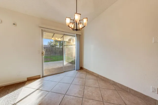 a view of an empty room with a chandelier fan