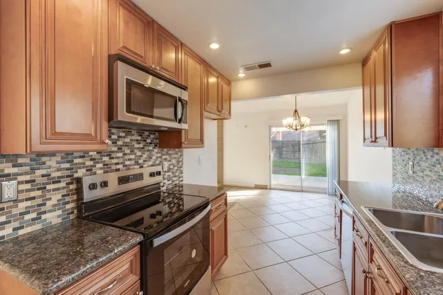 a kitchen with granite countertop a stove top oven microwave and cabinets