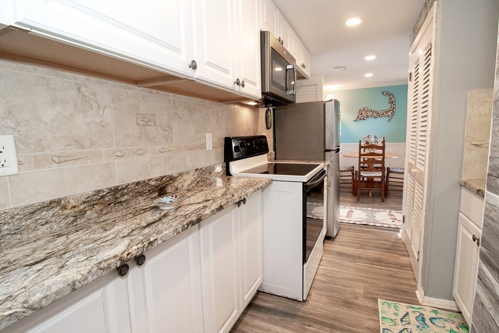 433 Lower County Road, Unit 25 Dennis, MA 02639 - Photo 7 of 32 a kitchen with stainless steel appliances granite countertop a lot of counter space and wooden floors