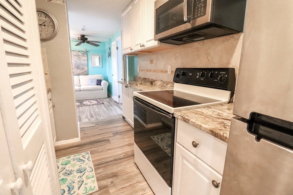 433 Lower County Road, Unit 25 Dennis, MA 02639 - Photo 10 of 32 a kitchen with granite countertop a sink and a stove next to a window
