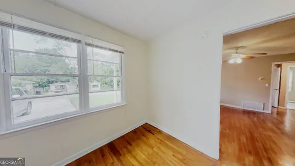 an empty room with wooden floor and windows