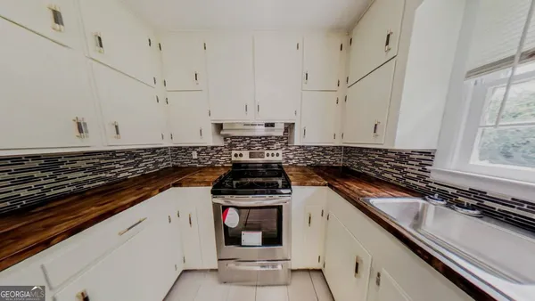 a kitchen with granite countertop a sink stove and cabinets